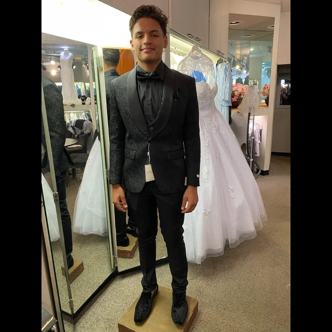 Client in black damask pattern tuxedo with matching boots and bow tie