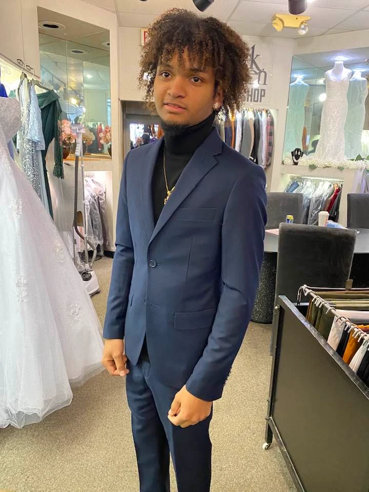 Client in navy blue suit with black turtleneck and gold chain