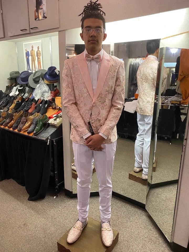 Client trying on pink embroidered prom suit with matching bow tie and loafers