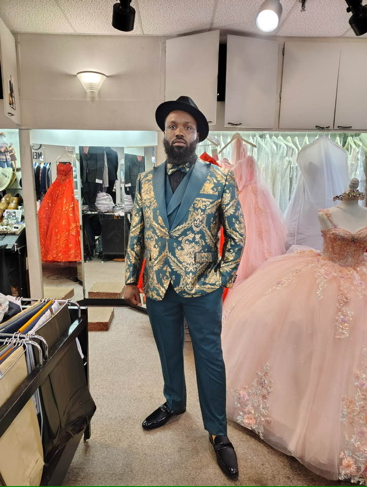 Adult client in teal and gold baroque blazer with black fedora and matching loafers